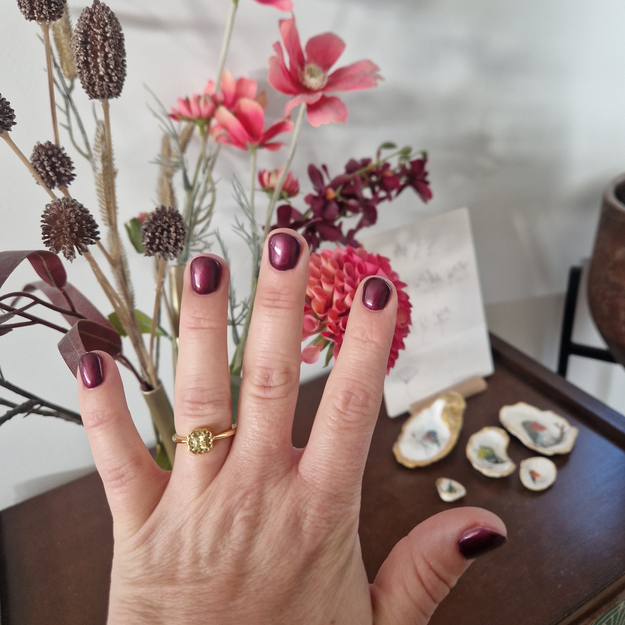 Donkerrode nagels bij een bos bloemen