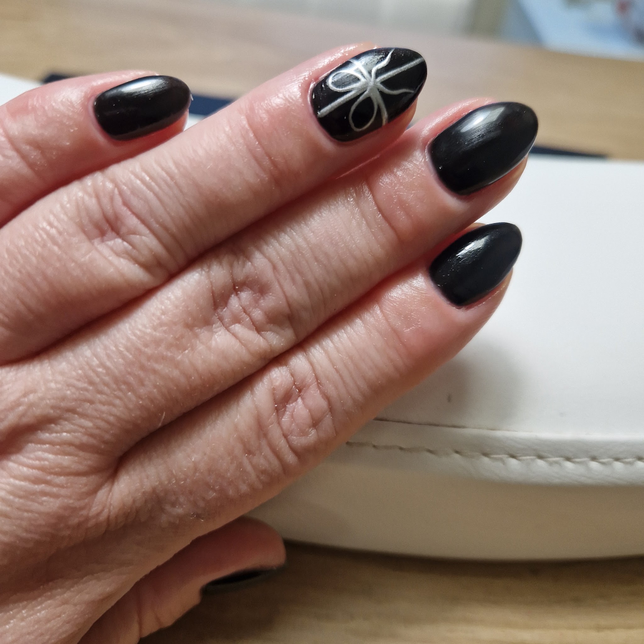 Zwarte nagels met een witte strik als nailart